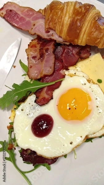 Obraz Open Croissant Sandwich with Fried Egg, Bacon, Cheese, and Arugula on a White Plate