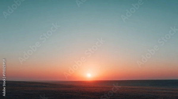 Fototapeta wide open field with warm orange glow at sunset, smooth clear sky transitioning from orange to pale blue, minimalist summer dusk scene with ample negative space