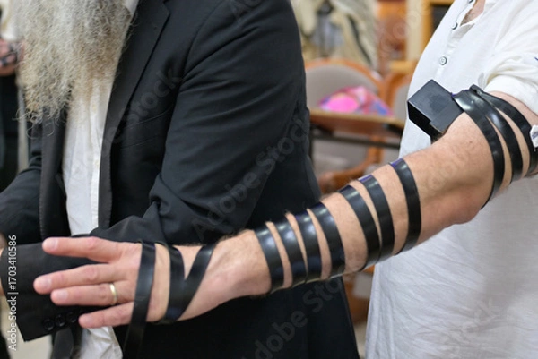 Obraz Father puts on tefillin at son's bar mitzvah in synagogue