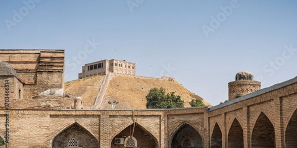 Fototapeta Landscape view of ancient madrasa kunha with Hissar aka Hisor fortress in background, historic medieval landmark of Tajikistan	
