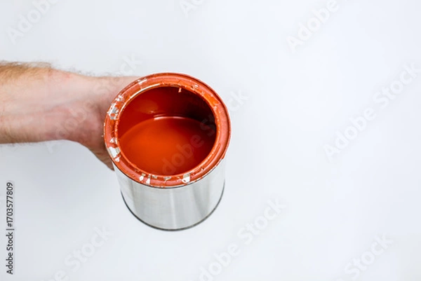 Fototapeta Red paint flowing down from can on white background