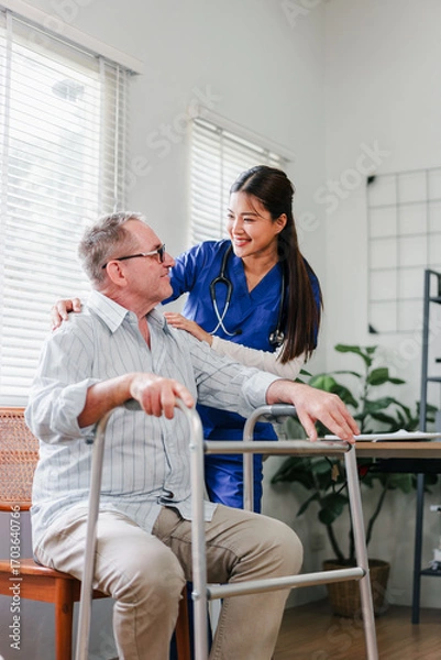 Fototapeta Elderly man with walker receiving supportive care from smiling female nurse in home setting, warm compassionate moment of assistance and recovery