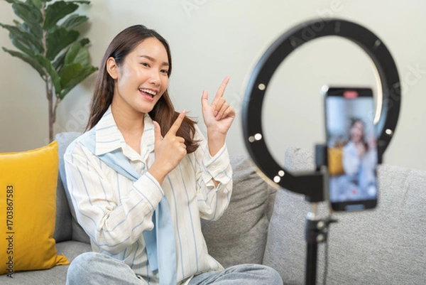 Fototapeta Influencer live internet, happy vlog asian young woman blogger using smart phone talking on video streaming podcast review online on social media, digital marketing with mobile content creator concept