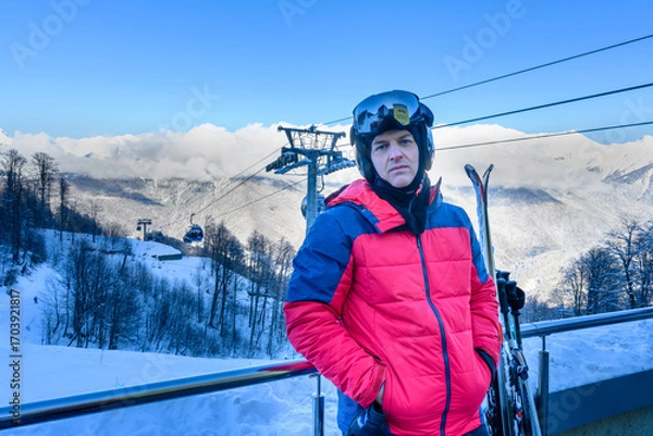 Fototapeta A skier in front of snow-covered mountains, getting ready for a descent