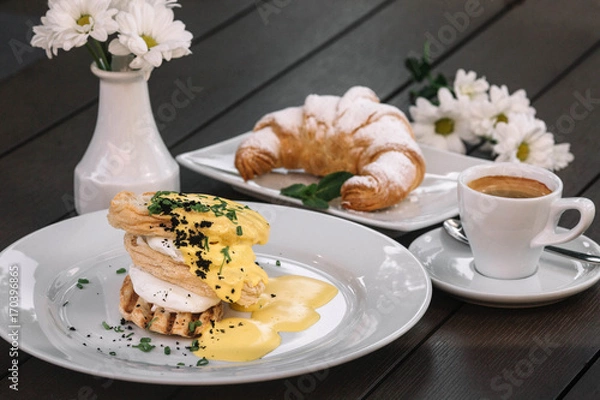 Obraz Poached eggs sandwich for breakfast with croissant,  coffee and chamomile on dark wood background