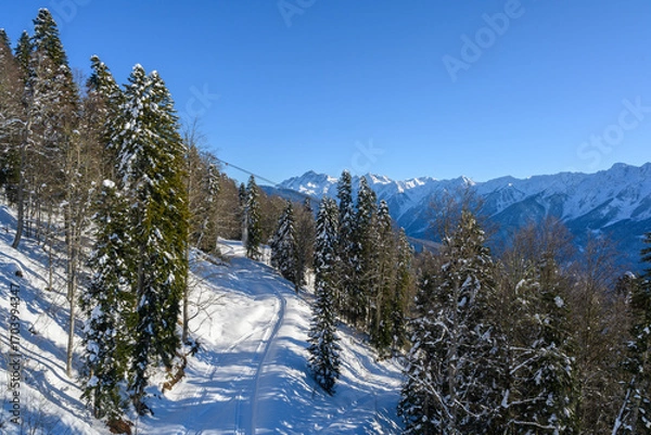 Fototapeta Ski resort view with snow-covered slopes and mountain peaks.
