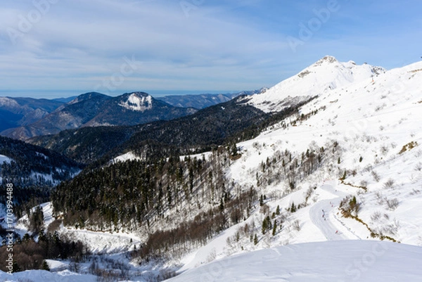 Fototapeta A clear view of snow-covered mountains from the top of a ski slope.