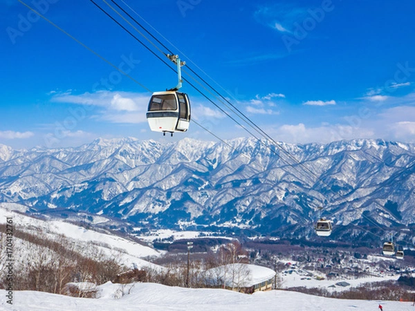 Fototapeta A gondola lift ascending ski slopes  with a panoramic view of the snowy valley (Tsugaike Kogen, Hakuba, Nagano, Japan)