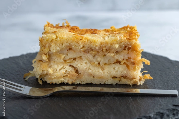 Fototapeta Moist layered apple semolina pie with crispy golden topping and fork.