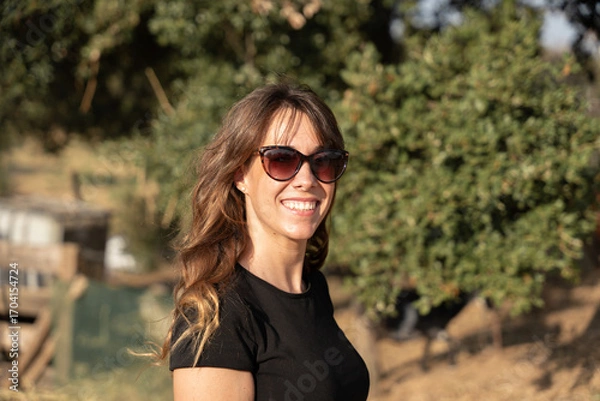 Fototapeta Farmer smiling and wearing sunglasses in front of olive trees