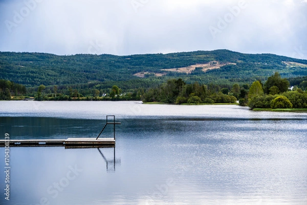 Fototapeta Peaceful Lakeside View with Dock and Forested Hills