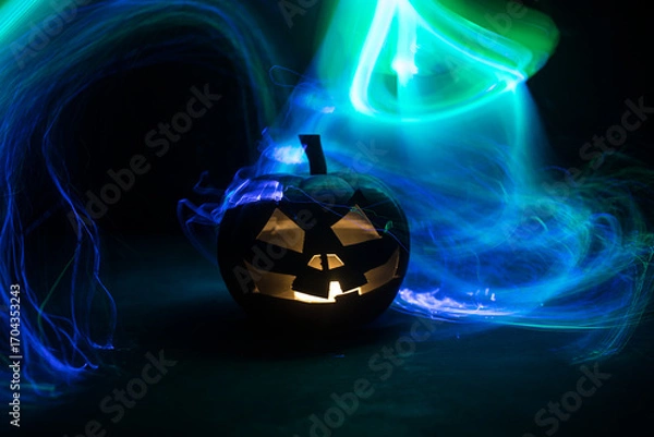 Fototapeta Halloween concept. Creepy silhouette in the dark corridor with pumpkin head. Toned light with fog on background.
