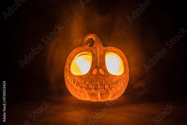 Fototapeta Halloween concept. Creepy silhouette in the dark corridor with pumpkin head. Toned light with fog on background.