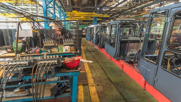 Fototapeta Conveyor assembly stage the body of tractor at big industrial factory timelapse