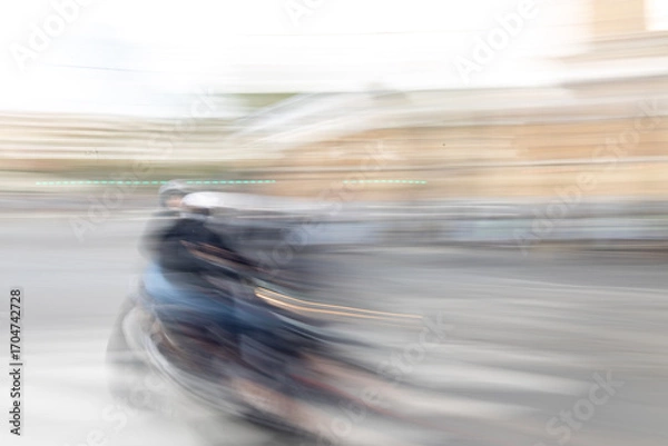 Fototapeta Blurred motion image of a motorcyclist riding fast on city street with SELECTIVE FOCUS, creating abstract light trails