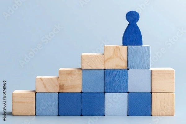 Fototapeta Wooden blocks form a stairway, with a blue figure at the top