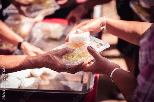 Fototapeta Receiving food for the poor from volunteers, concept of feeding, Homeless people receive delicious charity food from volunteers: concept of helping by donating food