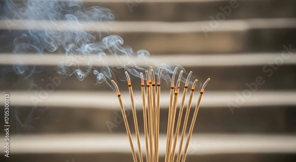 Obraz Incense sticks burning with smoke rising against a blurred background.