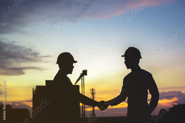 Fototapeta Smiling young architect or engineering builder in hard hat with tablet over group of builders at construction site, architect watching some a construction, business, building, industry, people concept