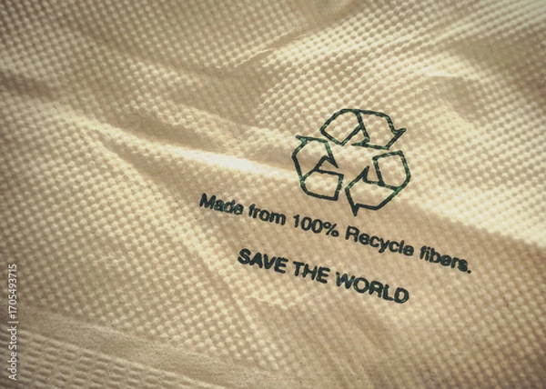 Fototapeta Close-up shot of a paper product made from 100% recycled fibers, with the recycling symbol and text "SAVE THE WORLD," promoting sustainability.