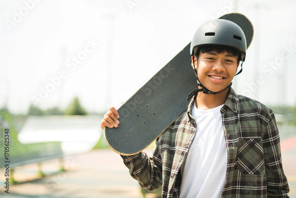 Fototapeta nice Boy with skateboards outside on skate playground