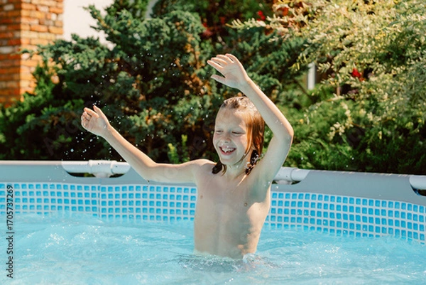 Fototapeta A young boy splashes joyfully in a swimming pool on a sunny day. He interacts playfully with his father and brother, creating cherished memories by the water.