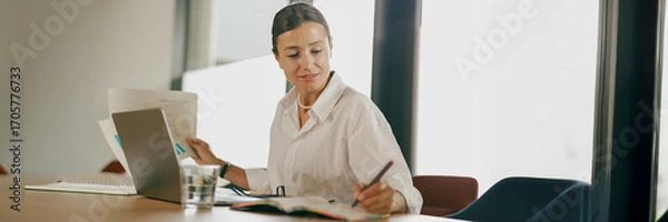 Fototapeta A Focused and Professional Woman Engaged in Tasks in a Modern Office Environment