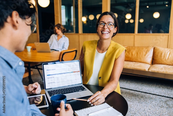 Fototapeta Smiling professional woman discussing a project in a modern office setting
