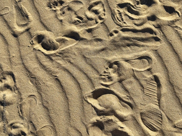 Fototapeta Beach sand with human footprints. Closeup texture of granular surface with natural wavy lines, steps