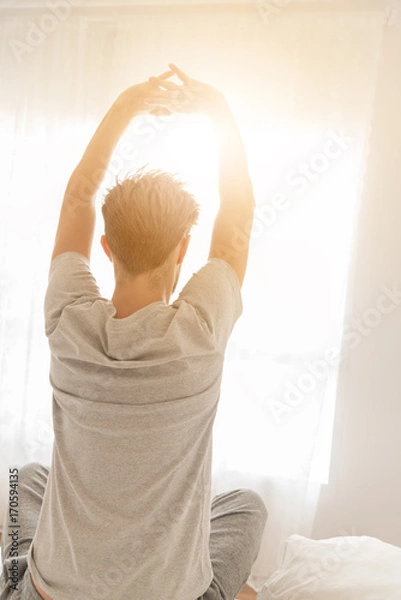 Obraz A handsome man stretching in bed after wake up in the morning at home