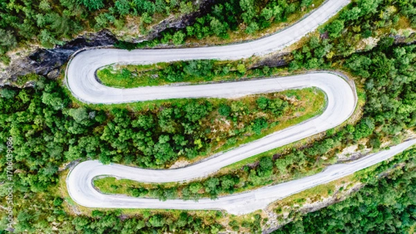 Fototapeta Captivating view of a winding road nestled amidst vibrant green foliage in Fortun, Norway. The road offers a thrilling journey through the breathtaking Norwegian landscape, ideal for exploration.