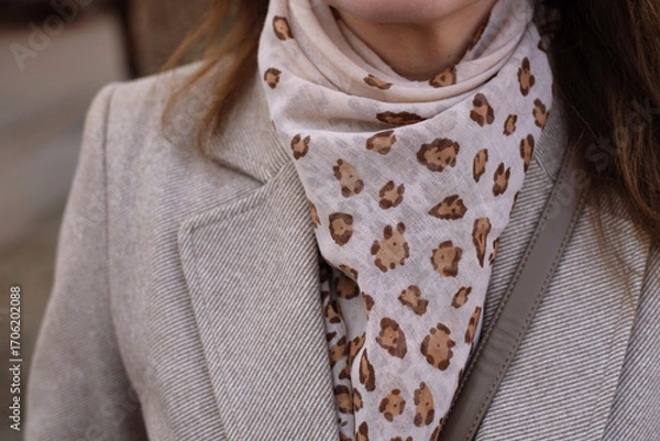 Fototapeta Stylish Beige Coat with Leopard Print Scarf and Minimalist Details. Close-up view of a chic beige coat complemented by trendy leopard print scarf, the neutral tones and elegant style