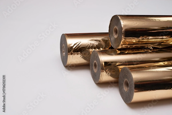 Fototapeta Metallic gold foil in rolls used in printing to transfer logo text through embossing onto finished printed products as decoration, space for text