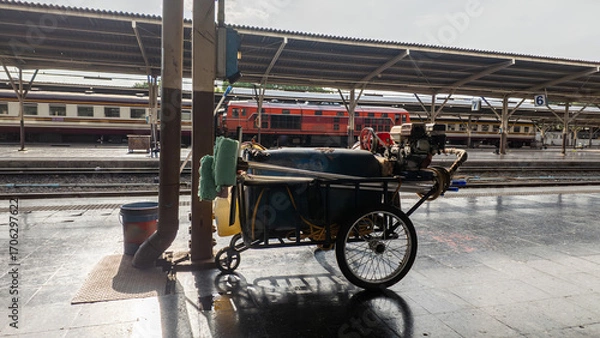 Fototapeta cleaning cart with hose and bucket at railway station, mobile trolley for platform sanitation, daily rail service and maintenance routine