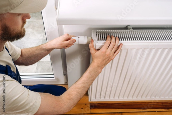 Fototapeta Plumber installing a modern radiator for efficient home heating during winter