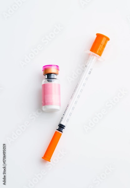 Fototapeta Small Pink Vial Next to Single Use Syringe on Light Background