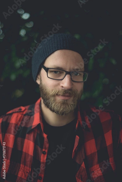 Obraz Happy hipster sitting outside with plants in the background.