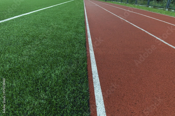 Obraz Running track and green grass field stadium