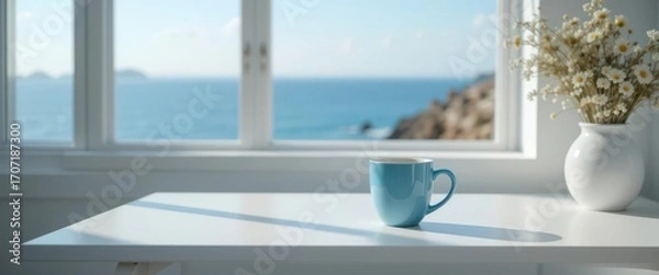 Fototapeta Bright Minimalist Workspace with Blue Coffee Mug Overlooking the Ocean.
