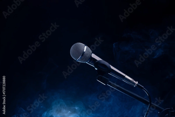 Fototapeta Black and silver microphone in studio, on a concert stage with fog and light coming from behind a black and dark background. Professional recording equipment.
