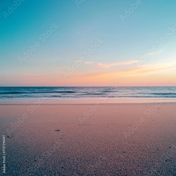 Fototapeta Close-up of beach sand with a clear blue summer sky above. Wide view of an empty, calm beach. Warm sunset colors the sky, creating a peaceful and relaxing summer scene.
