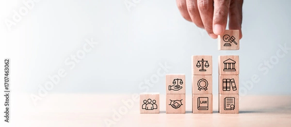 Fototapeta Business hand stacking wooden blocks with law and justice icons on light background. Concept of legal service, justice system, compliance, and business law consulting.