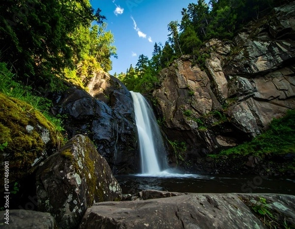Fototapeta Waterfall cascading down rocky cliffs in a lush forest (1)