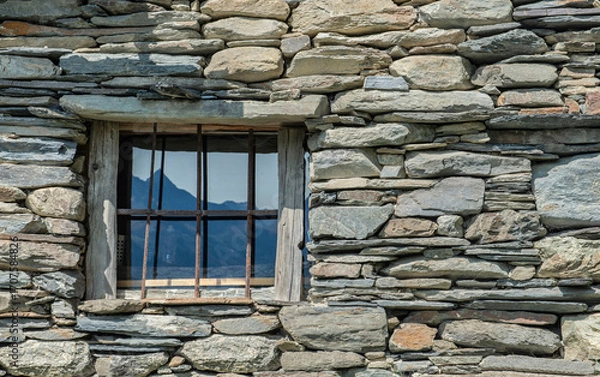 Fototapeta small window with bars of an alpine chalet in a french mountain village in stone