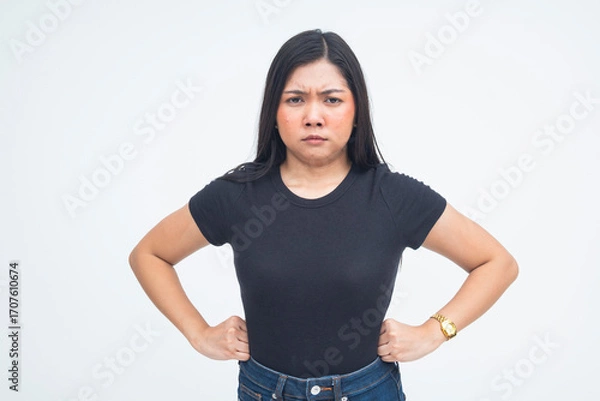 Fototapeta An infuriated young Asian woman in a half body shot with her hands on her waist, showing a confrontational stance and fierce expression. Isolated on a white background.