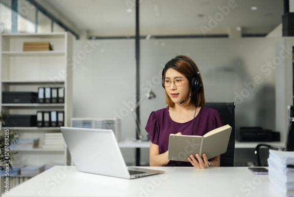Fototapeta Smiling woman in headphones taking notes, motivated interested student studying online, using tablet, watching webinar training or listening to lecture, remote education concept.