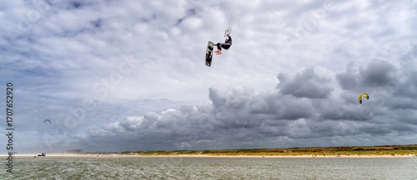 Fototapeta Kitesurfer Mid-Flight under Cloudy Skies at the Zandmotor Beach near The Hague