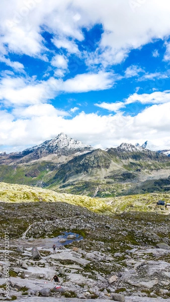 Fototapeta Austria, 08-2025 :wide shot of mountains and glaciers, near the weißsee lake. People hiking, Cloudy blue sky in background.