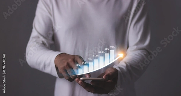 Fototapeta Young man with smartphone hand touching to visualize money growth The phone screen displays graphs and charts showing increasing investment and savings trends, along with an increased account balance