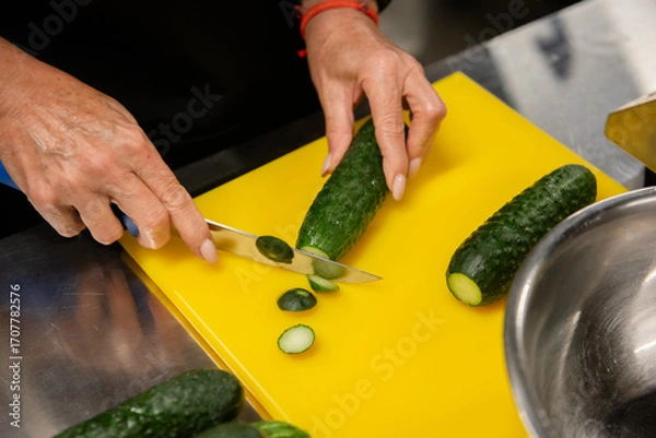 Obraz female hands cutting a cucumber